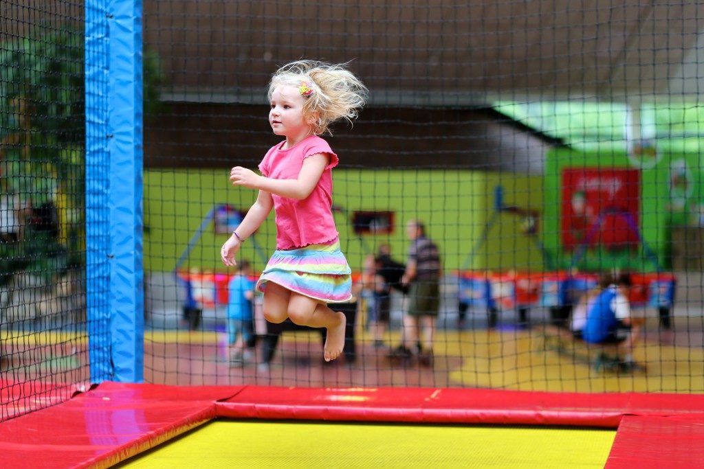 Little child jumping at trampoline in indoors playground